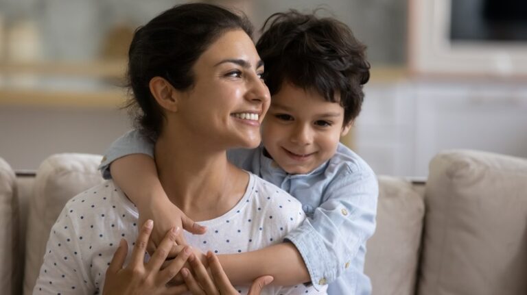 Young, smiling boy hugging mother