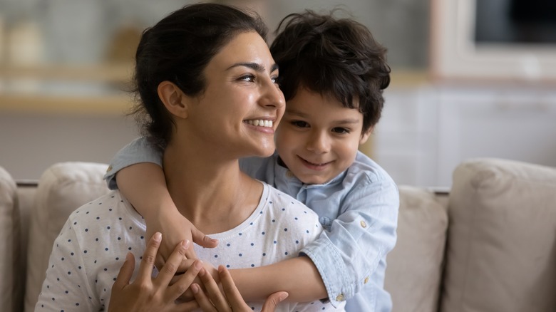 Young, smiling boy hugging mother
