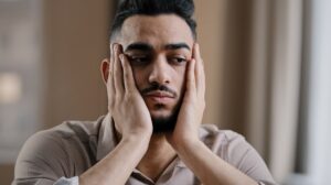 man holding his hands to his face in frustration