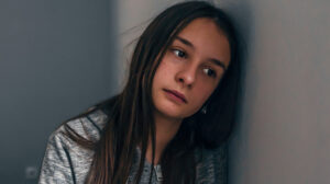 Sad teen girl leaning against wall