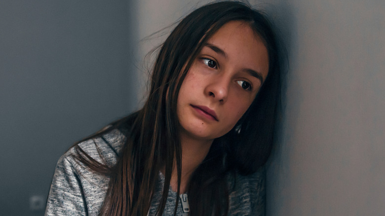 Sad teen girl leaning against wall