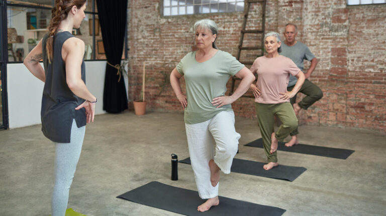 yoga instructor teaching tree pose to seniors