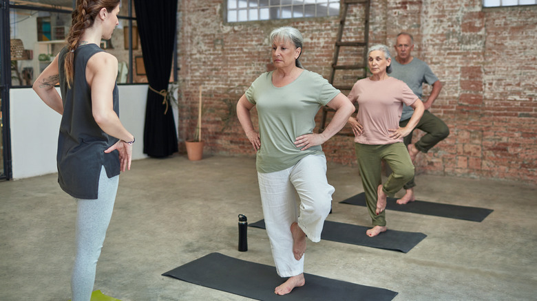 yoga instructor teaching tree pose to seniors