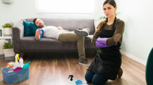 woman doing chores while husband watches tv