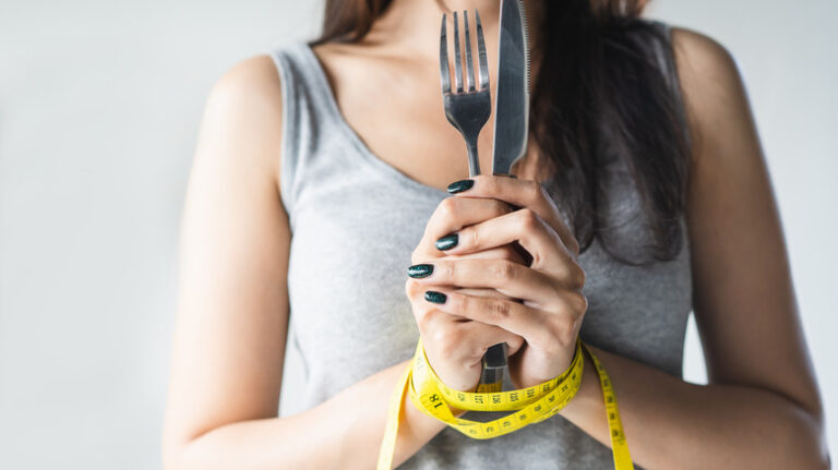 Hands wrapped in measuring tape, holding utensils
