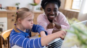 Girl with Down syndrome works with teacher