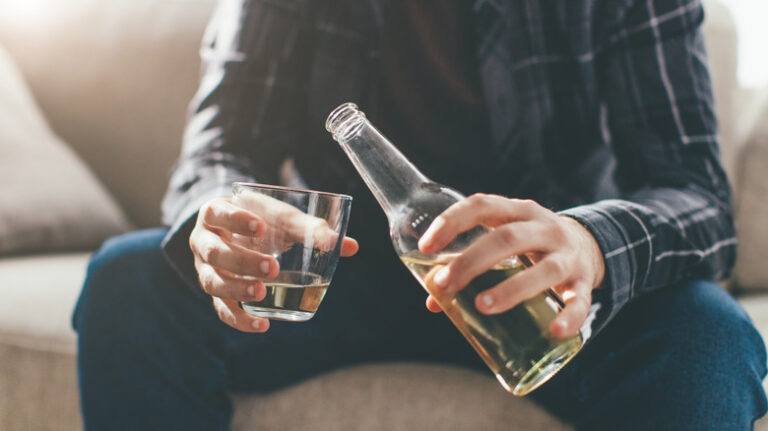 close-up of man pouring bottle of beer into a glass
