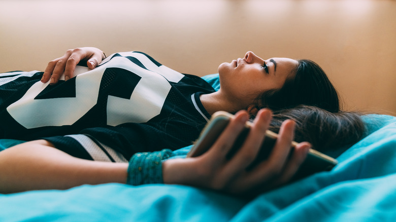 woman in bed holding phone