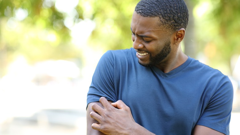 Man in pain scratching arm