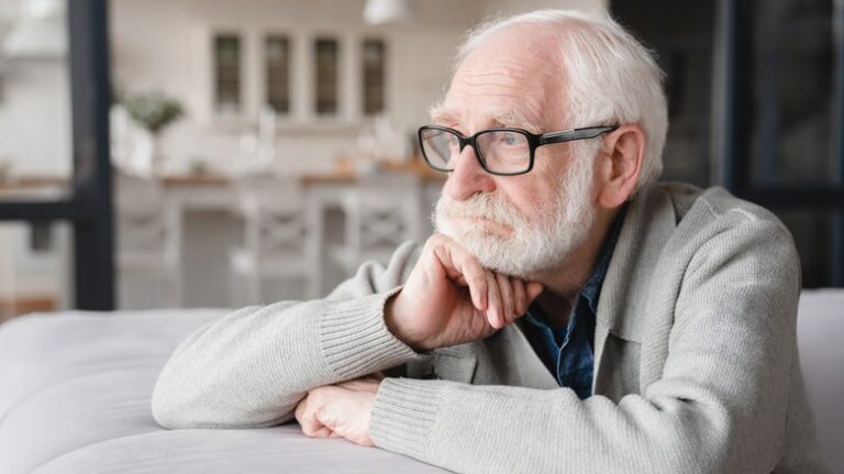 Distressed older man staring out window
