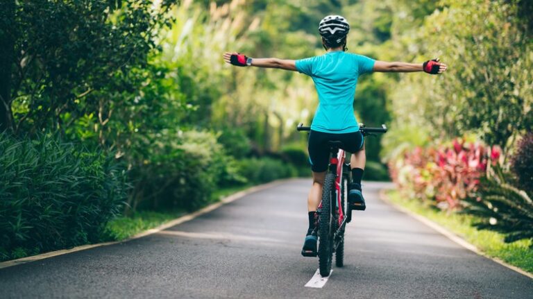 person arms outstretched cycling away