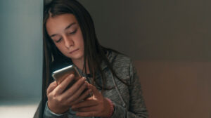Sad young girl looking at smartphone