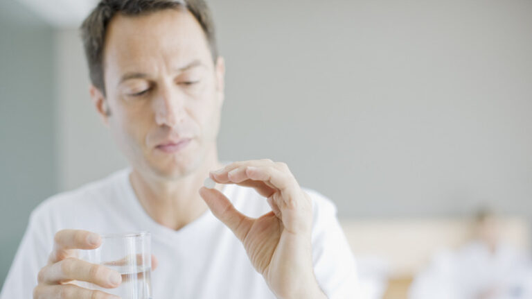 man looking at a pill