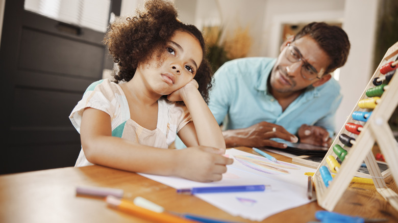 Child looking off into space with book in front of them