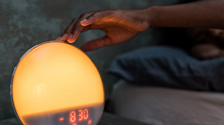 person reaching for their sunrise larm clock