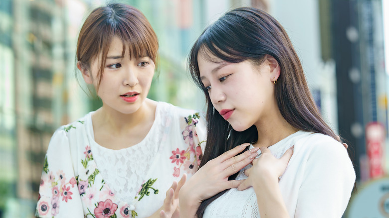 Worried friend helping woman breathe