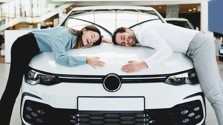 Happy couple hugging new car