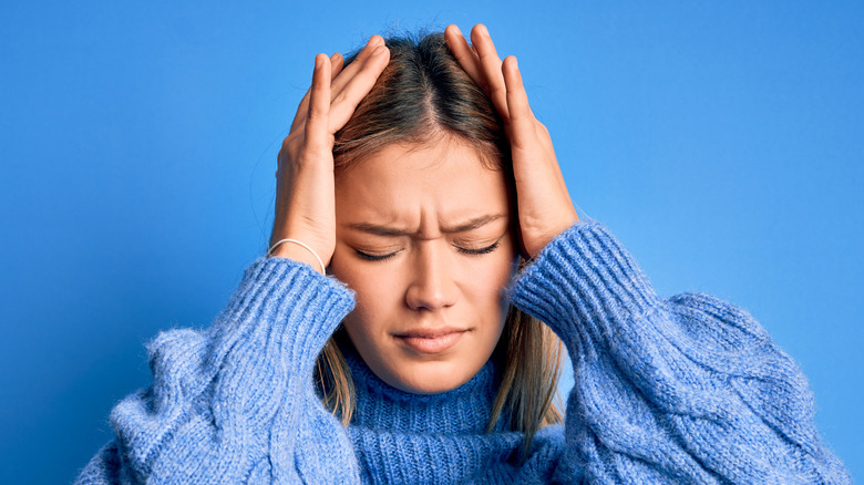 woman holding head in pain