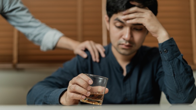 friend consoling man drinking alcohol 