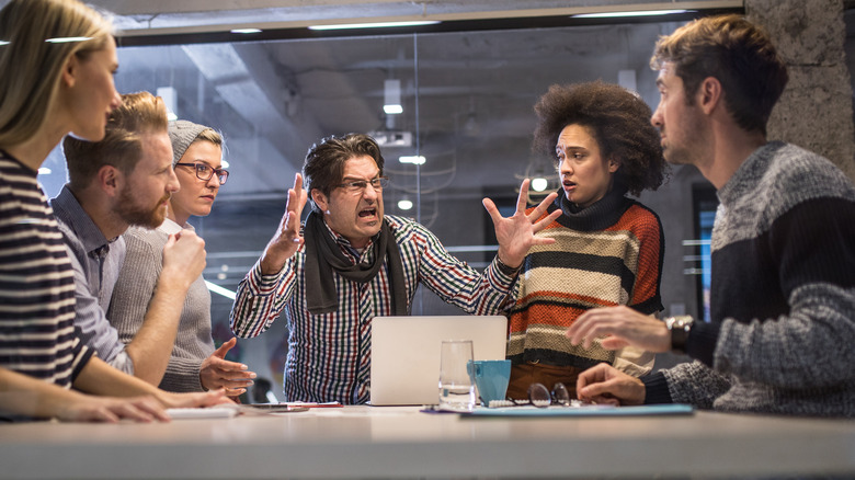 Angry manager yelling at co-workers at a meeting