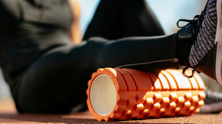 closeup of a person using a foam roller on their calves 