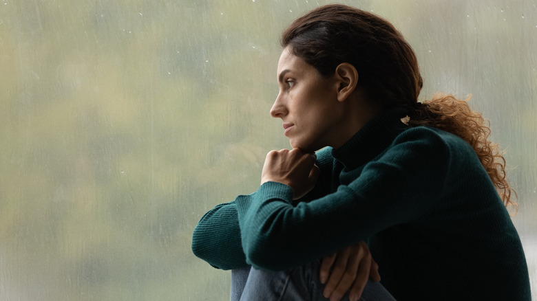 grieving woman sitting by a window