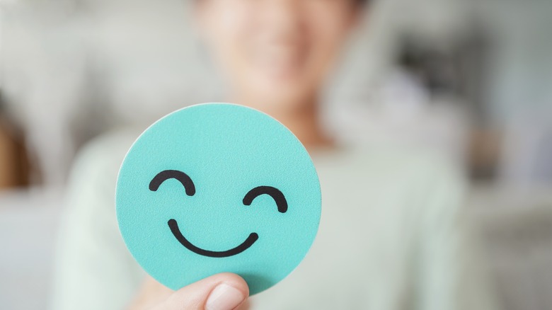 a hand holding a smiley face on green paper