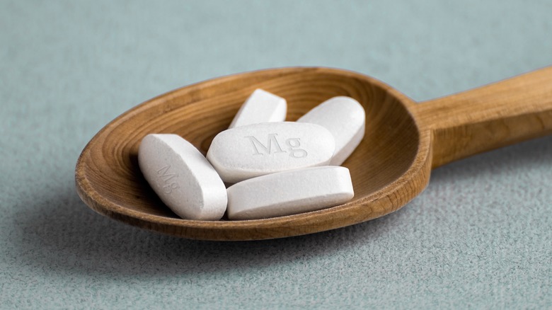 Wooden spoon holding magnesium pills