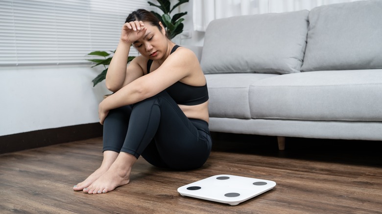 Upset Asian woman with scale