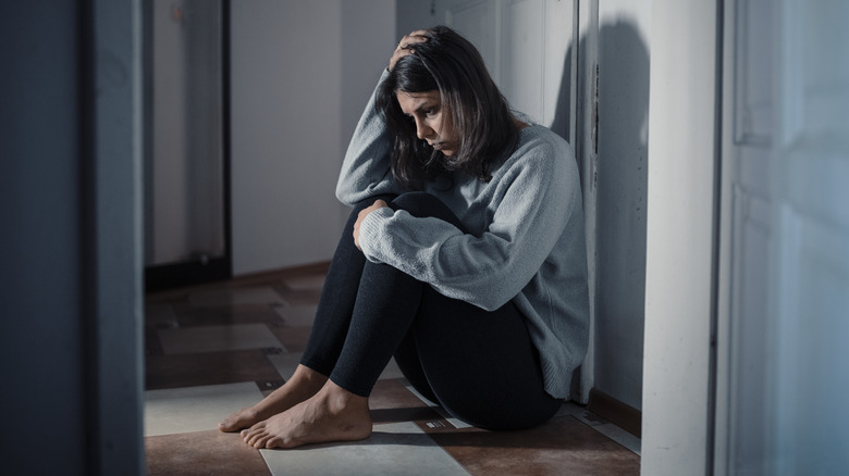 sad woman sitting on the floor of a hallway