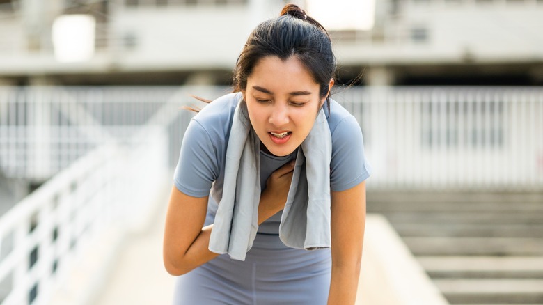 Young woman bends over in fatigue
