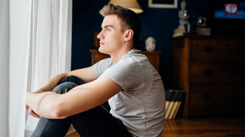 man looking out window