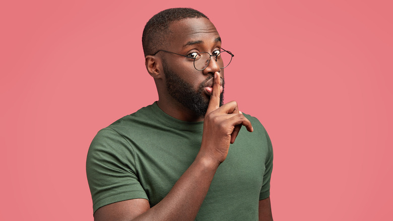 a man presses his fingers to his lips 