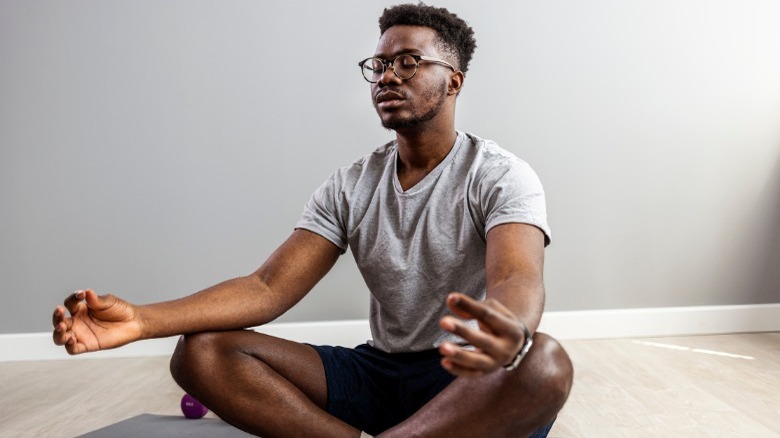 Young man meditating on floor