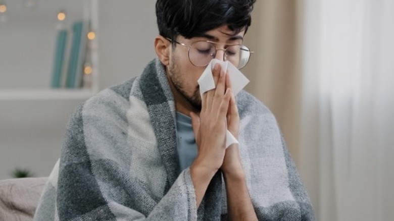 Young man blowing nose