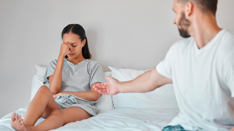 a man reaches out to crying woman in bed 