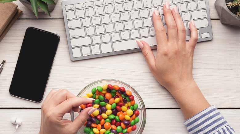 Woman working on keyboard while eating